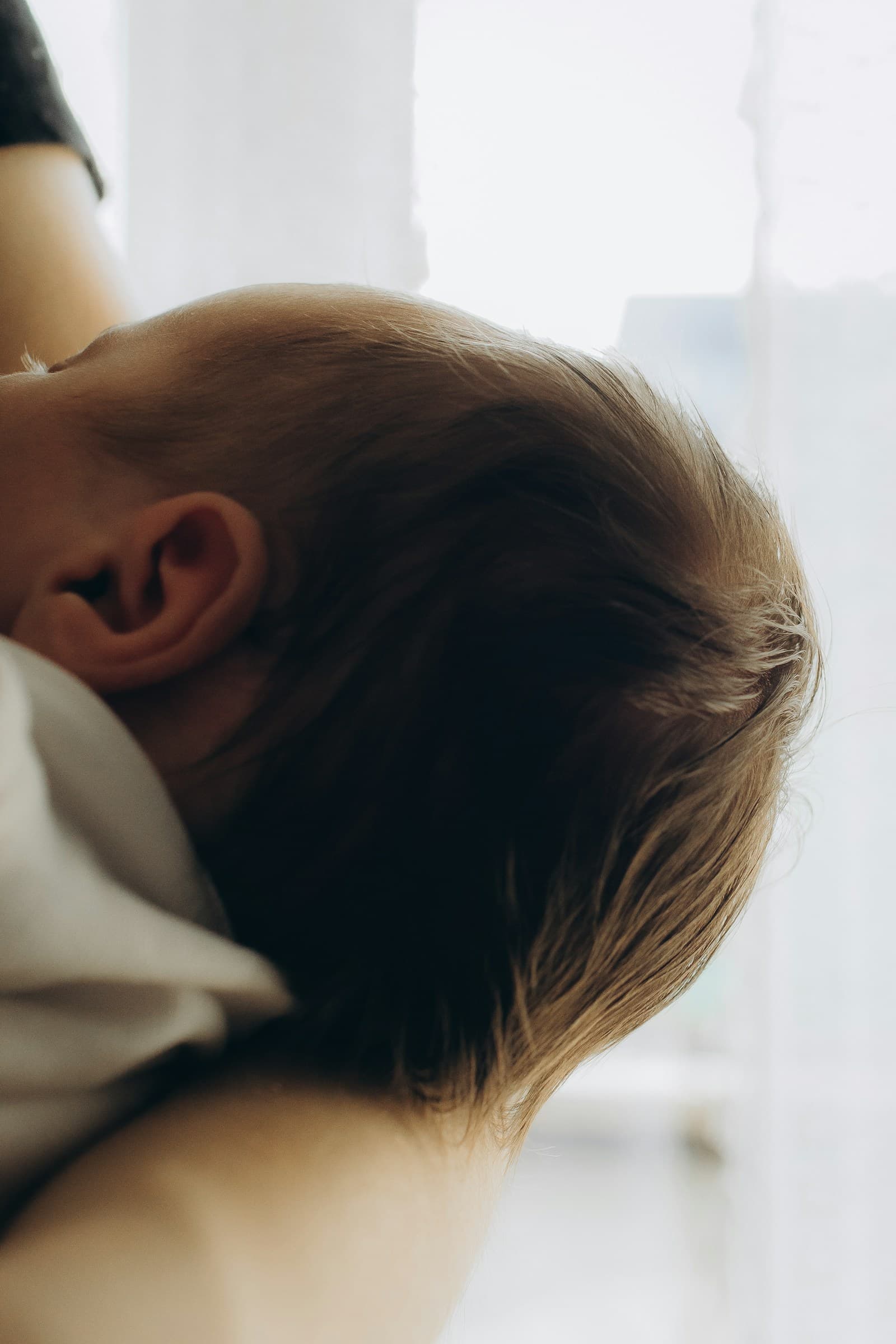 The back of a baby's head resting on a shoulder.